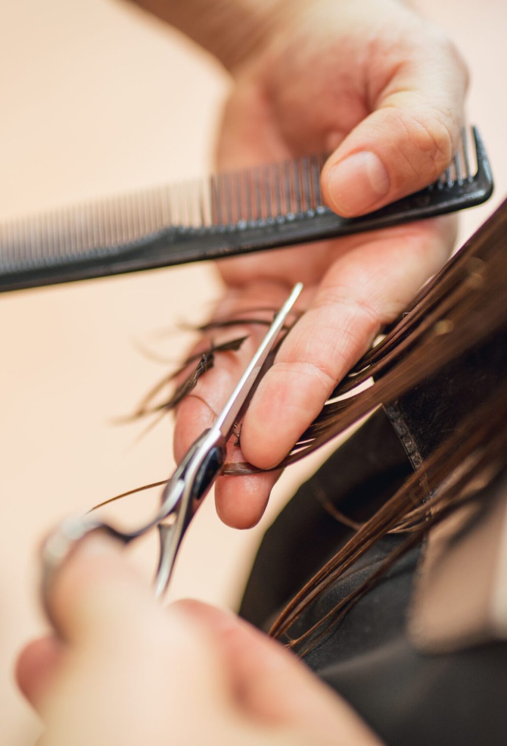Close-up of a  man hairdresser cutting the hair of a woman.