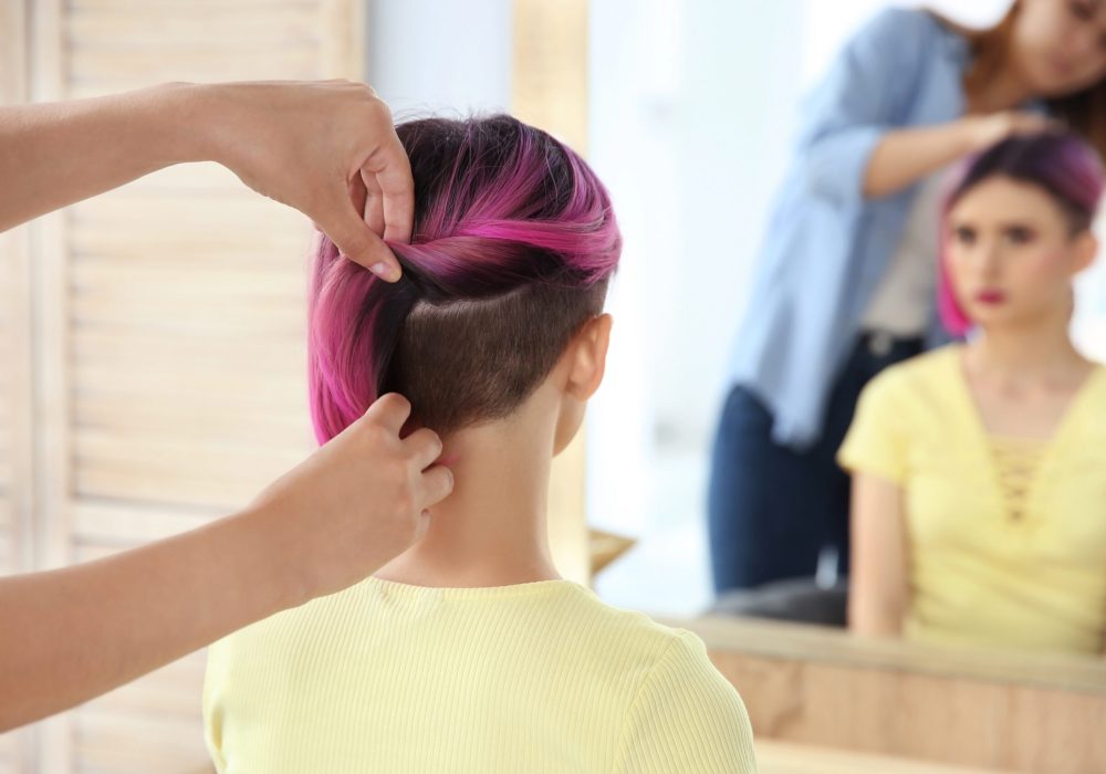 Professional hairdresser working with young woman in beauty salon. Trendy hair color