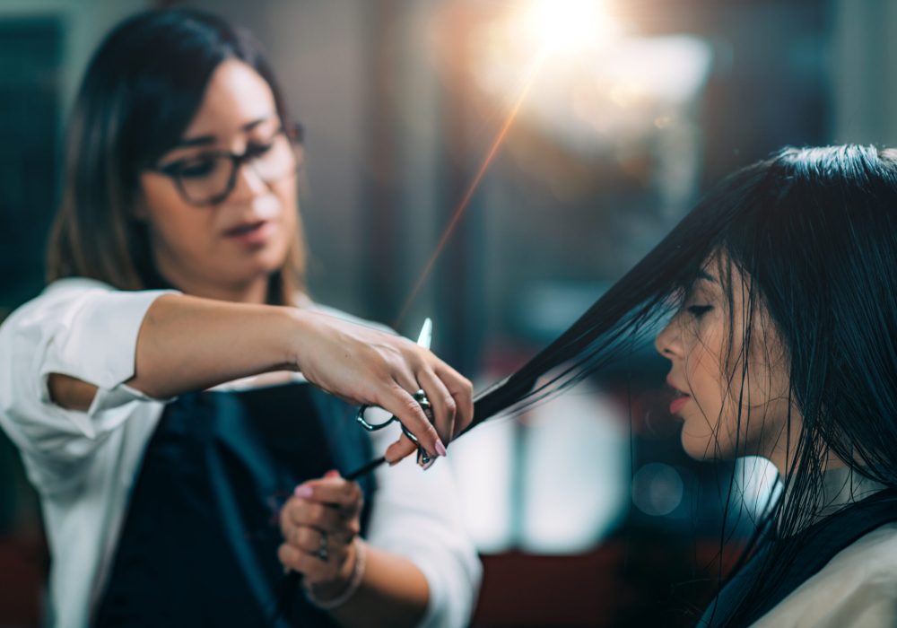 Young beautiful woman getting her hair cut by female hairdresser in beauty salon.
